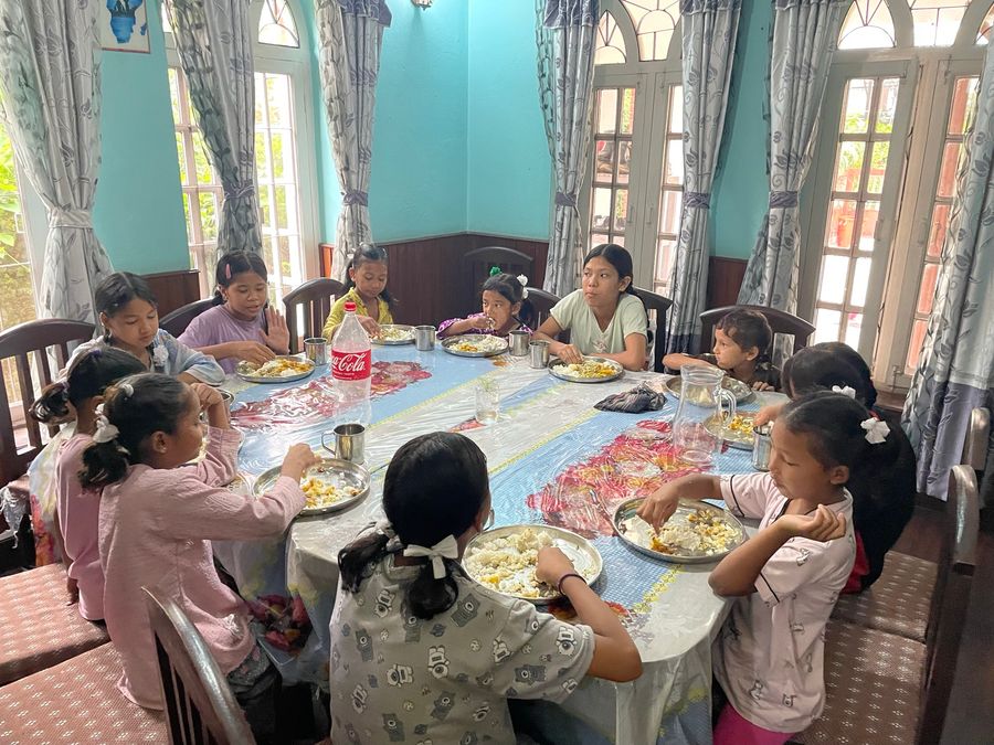 Children sharing a meal around the table at the hostel house