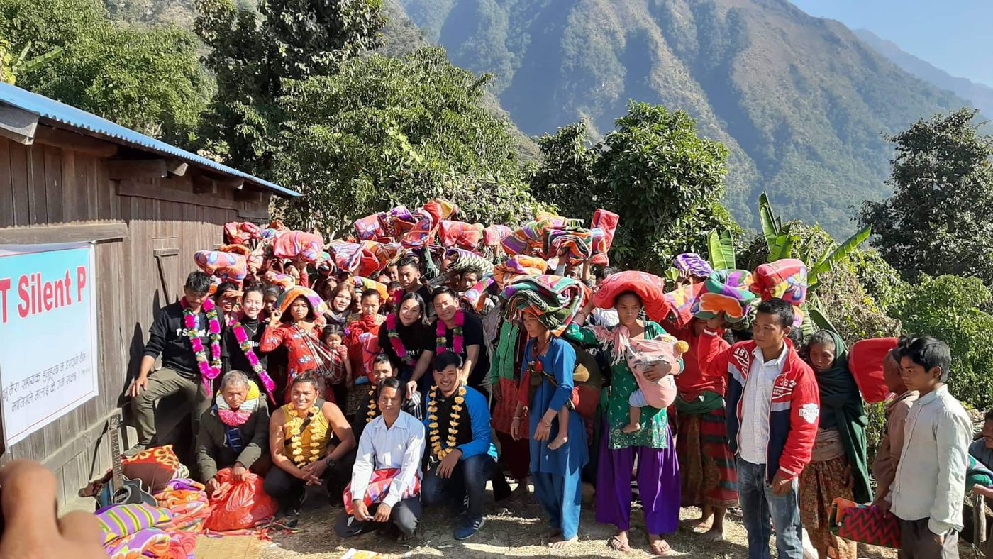 Blanket distribution with The Silent Partner banner in a mountain village