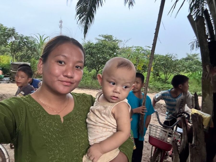 An outreach worker holding a baby during a village visit