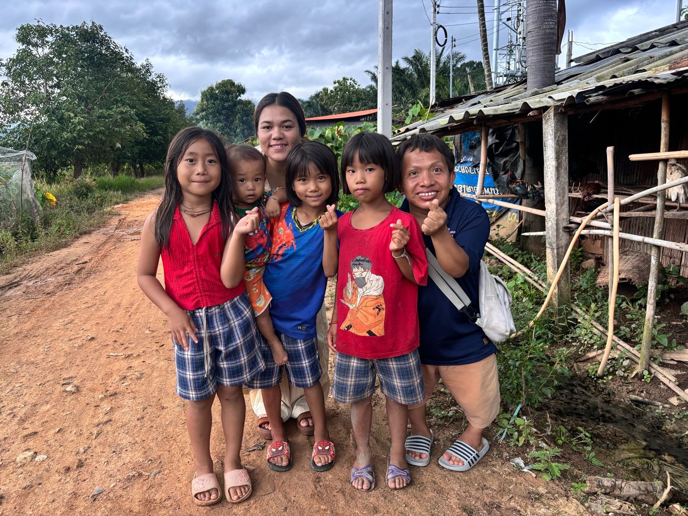Children and outreach workers smiling together on a village road